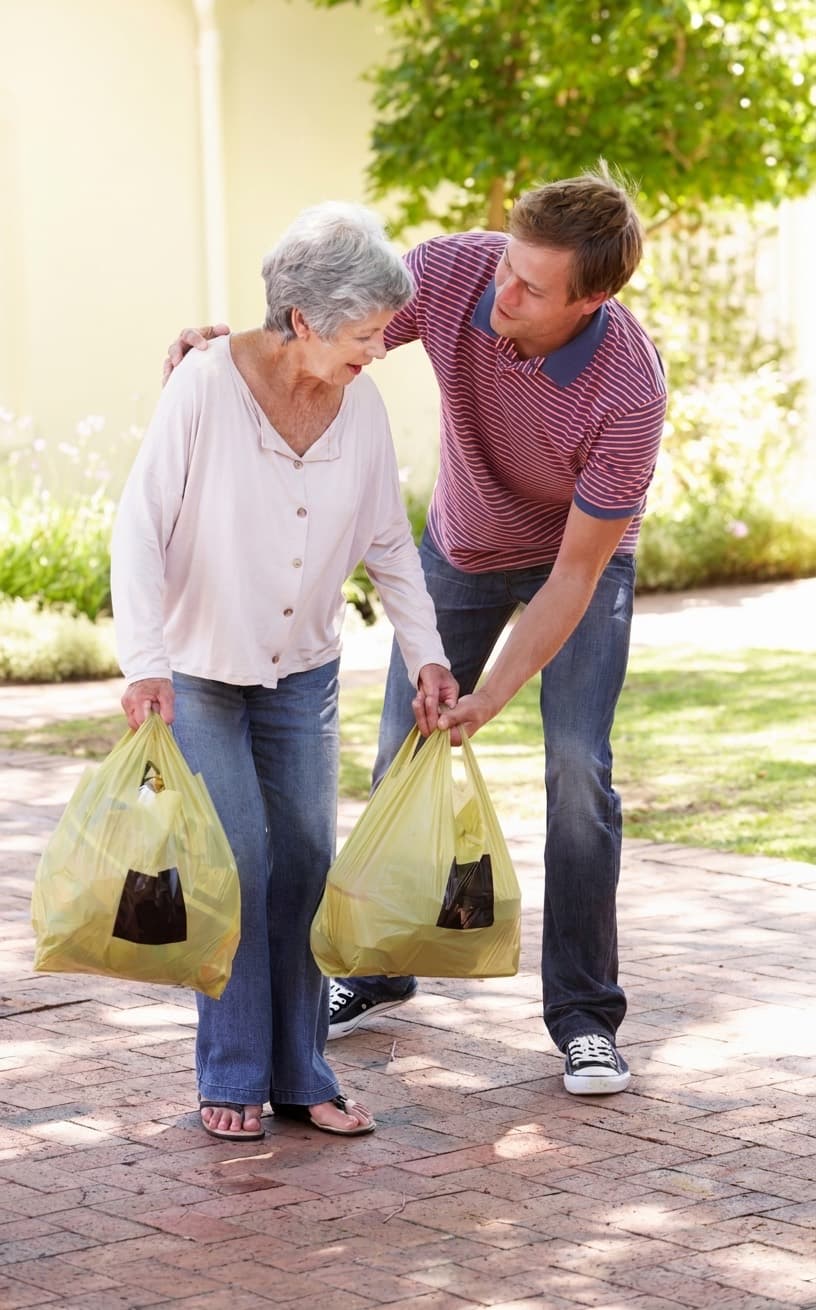 A rider walks back up the path with her grocery bags, a second pair of hands on the heavier one.