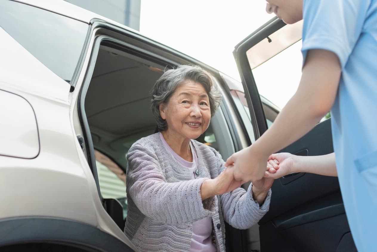 A rider takes a steadying hand at the open car door, the same hand at the same door as the week before.