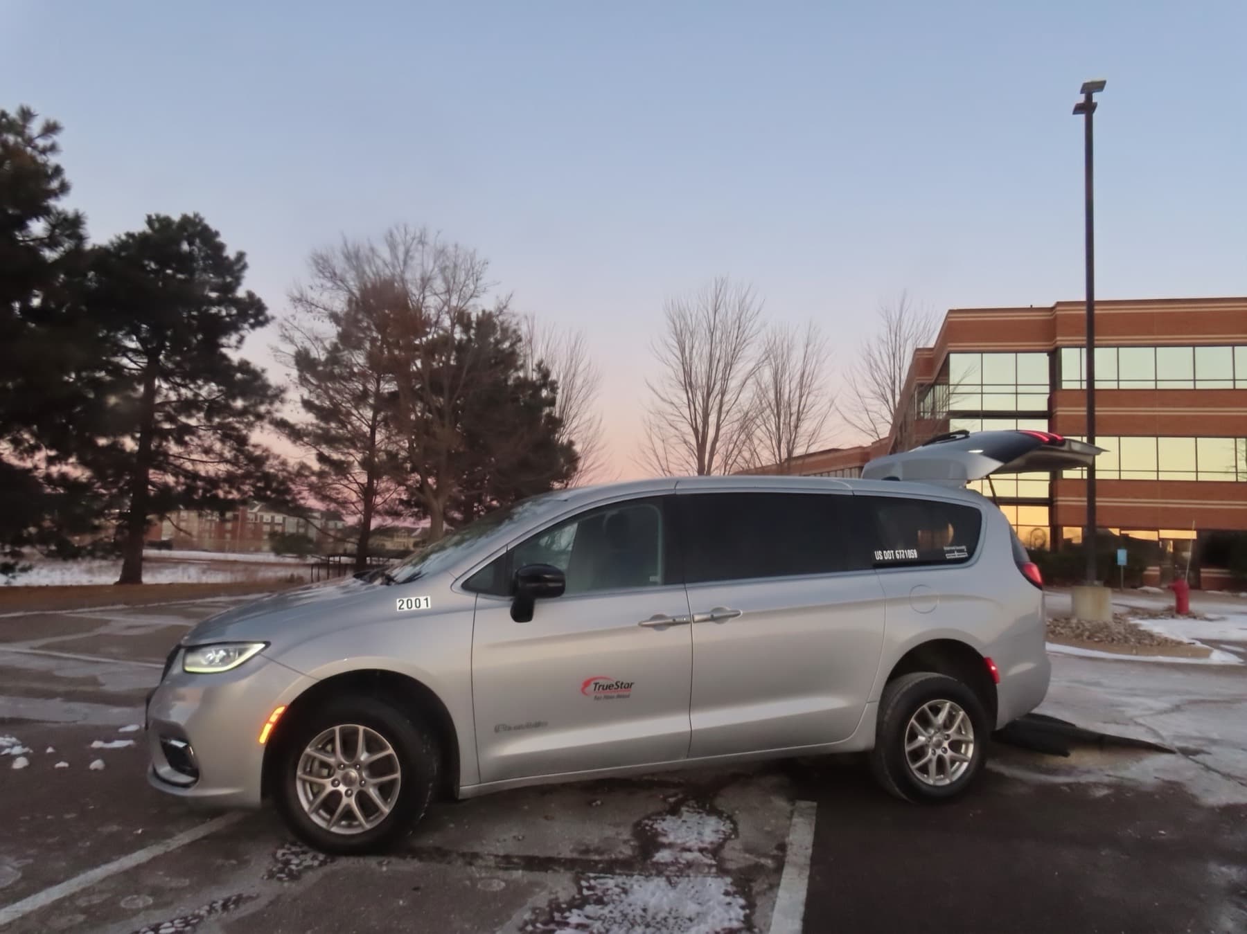 The van at dusk in the office lot, hatch up and the DOT number lit — parked at the ready for the next statewide run.