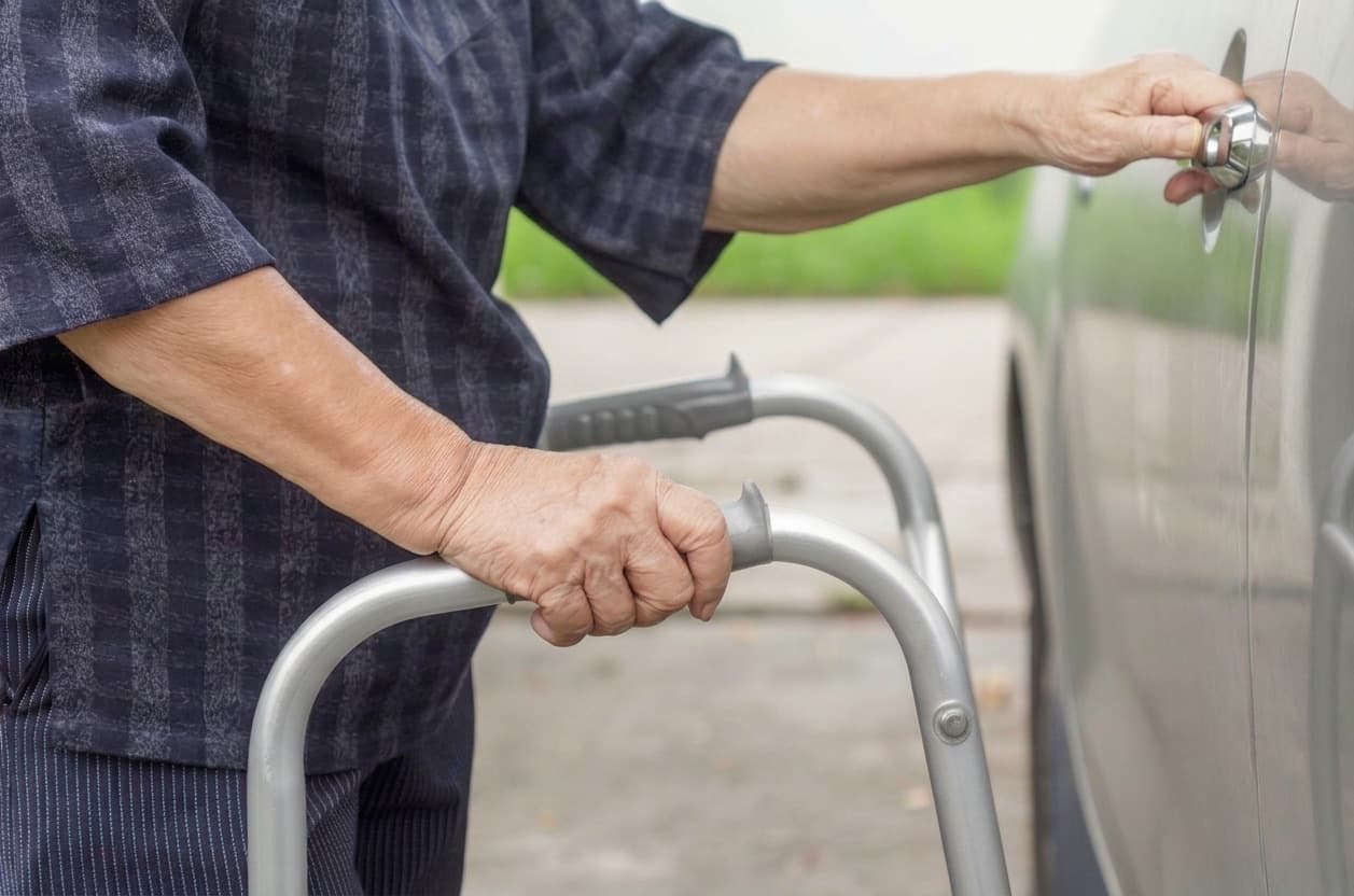 A rider steadies herself on her walker and reaches for the van's door handle.